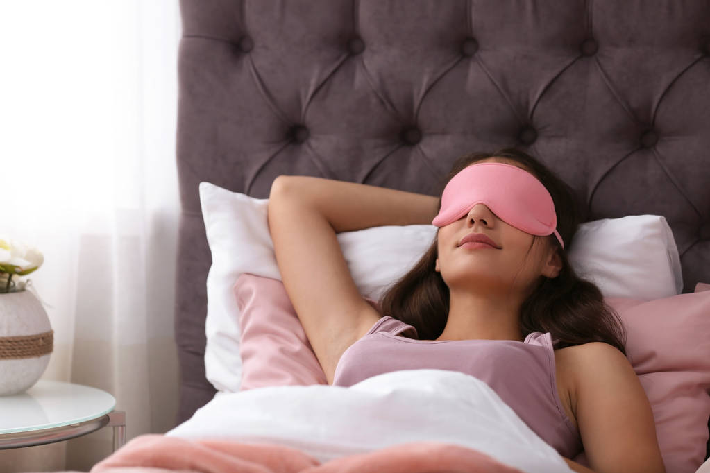 Молодая красивая женщина в маске спит в постели дома. Ранним утром
 - Фото, изображение