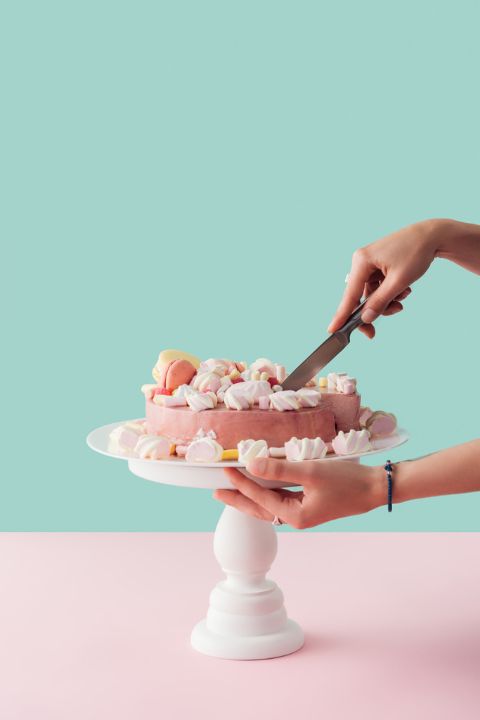 ナイフで女性ピンク マシュマロ ケーキカットのケーキ スタンド観トリミング - 写真・画像