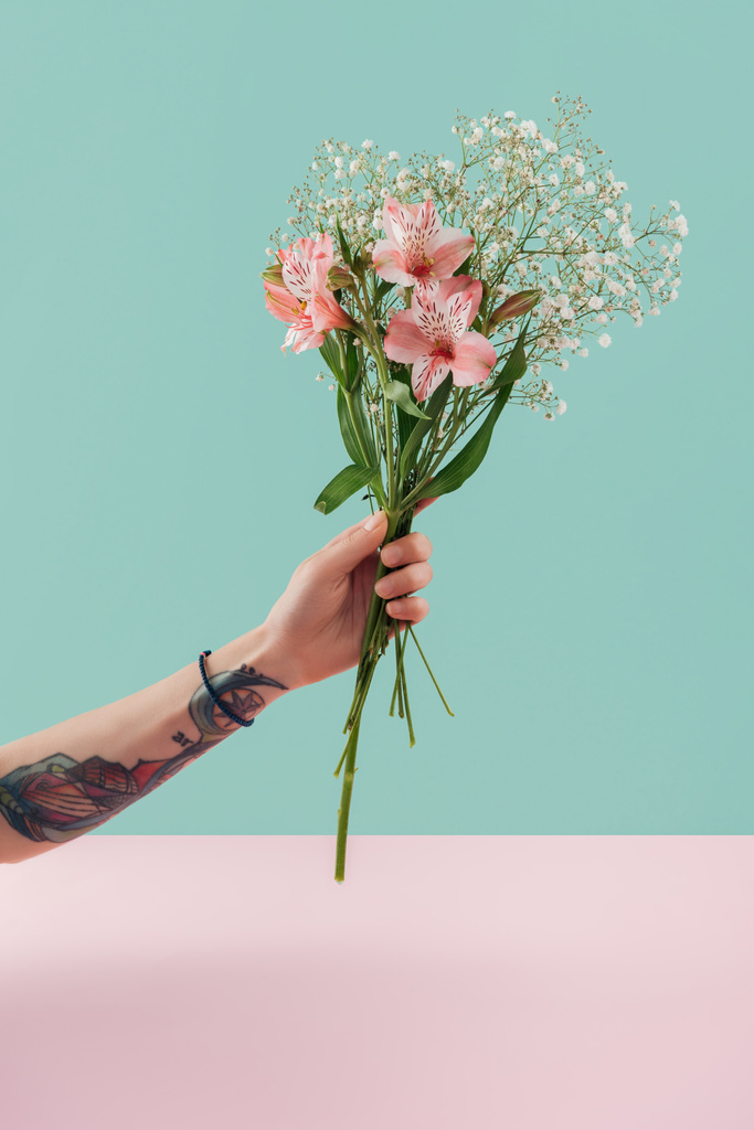 vista recortada de mujer tatuada sosteniendo ramo con flores de lirio rosa
 - Foto, Imagen