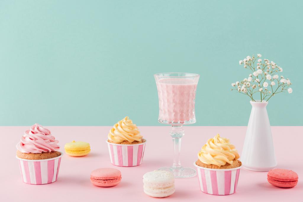 cupcakes et macarons sucrés et verre de milkshake sur fond pastel
  - Photo, image