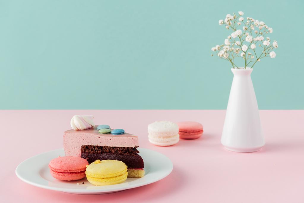 macarrones y un pedazo de pastel en plato con flores en jarrón
  - Foto, imagen
