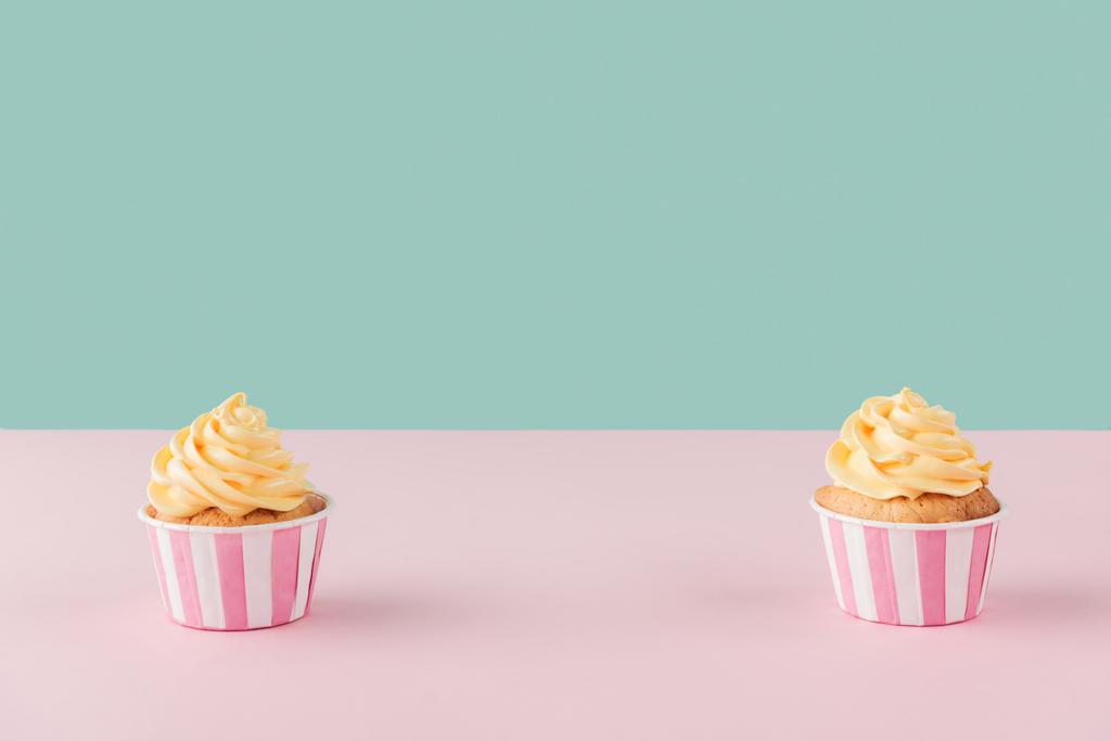 deux cupcakes à la crème au beurre sur fond pastel avec espace de copie
 - Photo, image
