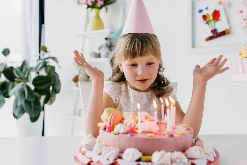cute kid with wide arms looking at birthday cake with candles  - Photo, Image