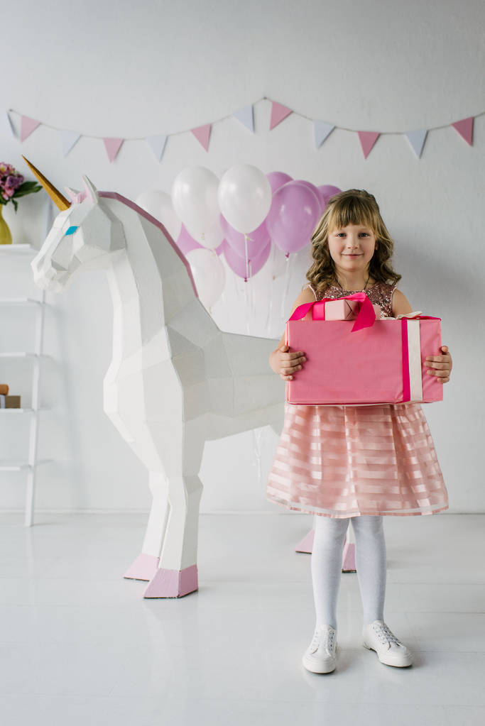 niño lindo cumpleaños celebración caja de regalo cerca de unicornio decorativo
  - Foto, imagen