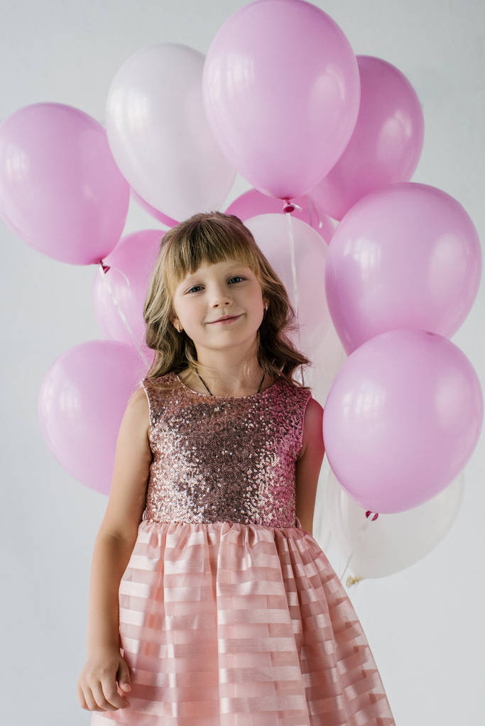 niño sonriente mirando a la cámara y sosteniendo un montón de globos de aire
  - Foto, Imagen