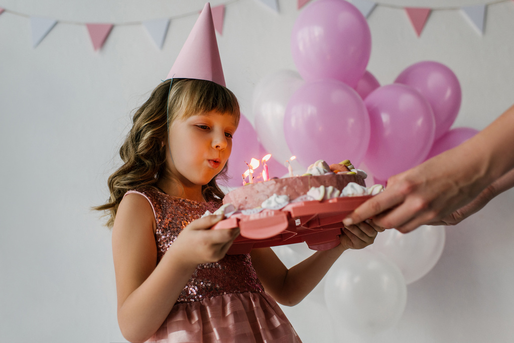 обрезанное изображение матери, держащей торт на день рождения, пока ребенок задувает свечи
  - Фото, изображение