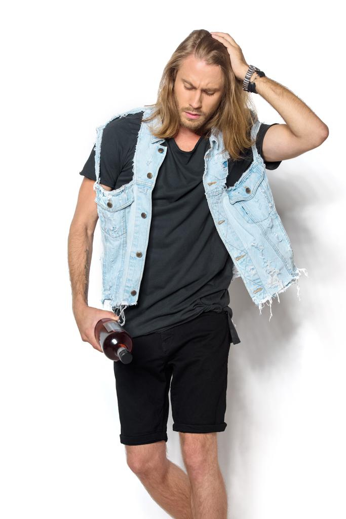 красивий молодий чоловік в джинсовому жилеті з пляшкою рому на білому
 - Фото, зображення