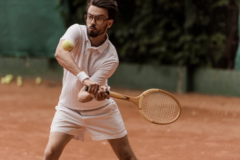 guapo jugador de tenis de estilo retro golpear la pelota en la cancha de tenis
 - Foto, imagen