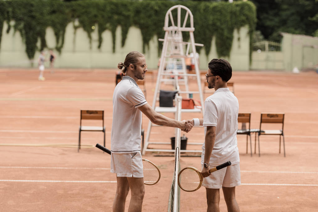boční pohled retro stylizovaný tenistů potřesení rukou nad tenisové sítě u soudu - Fotografie, Obrázek