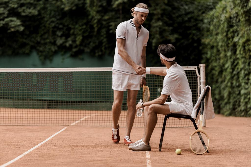 jugadores de tenis estilo retro estrechando la mano en la cancha de tenis
 - Foto, Imagen