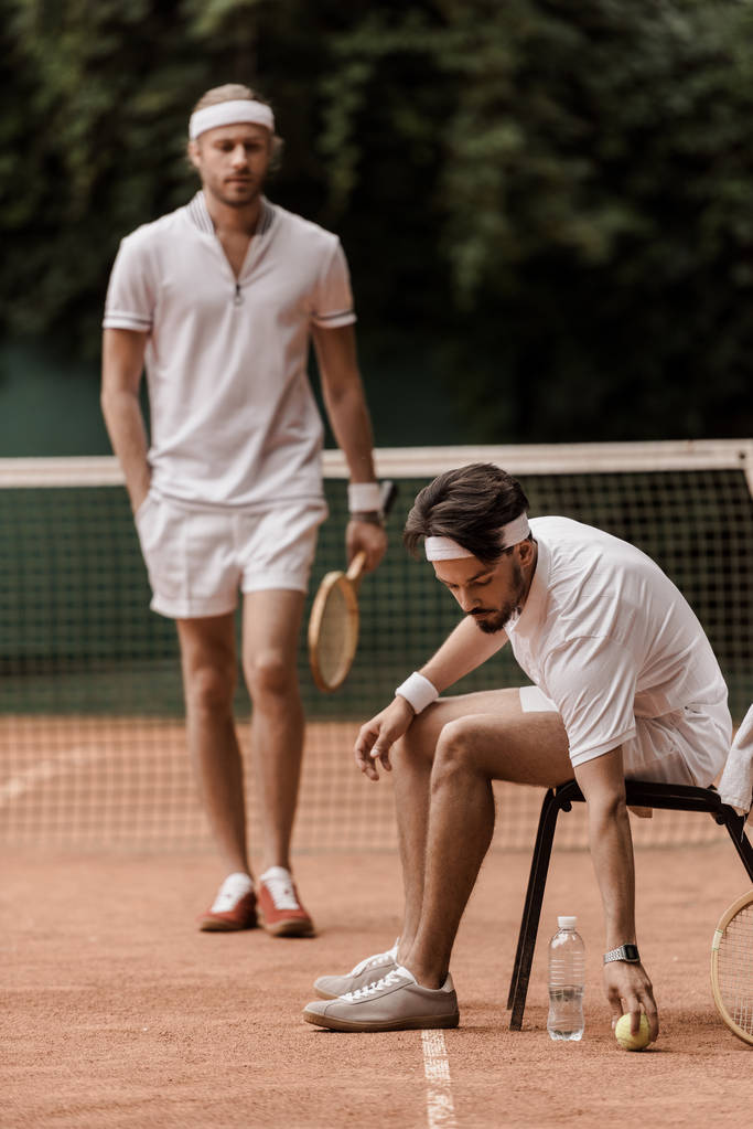 jugador de tenis de estilo retro poner pelota en el suelo en la cancha de tenis
 - Foto, Imagen