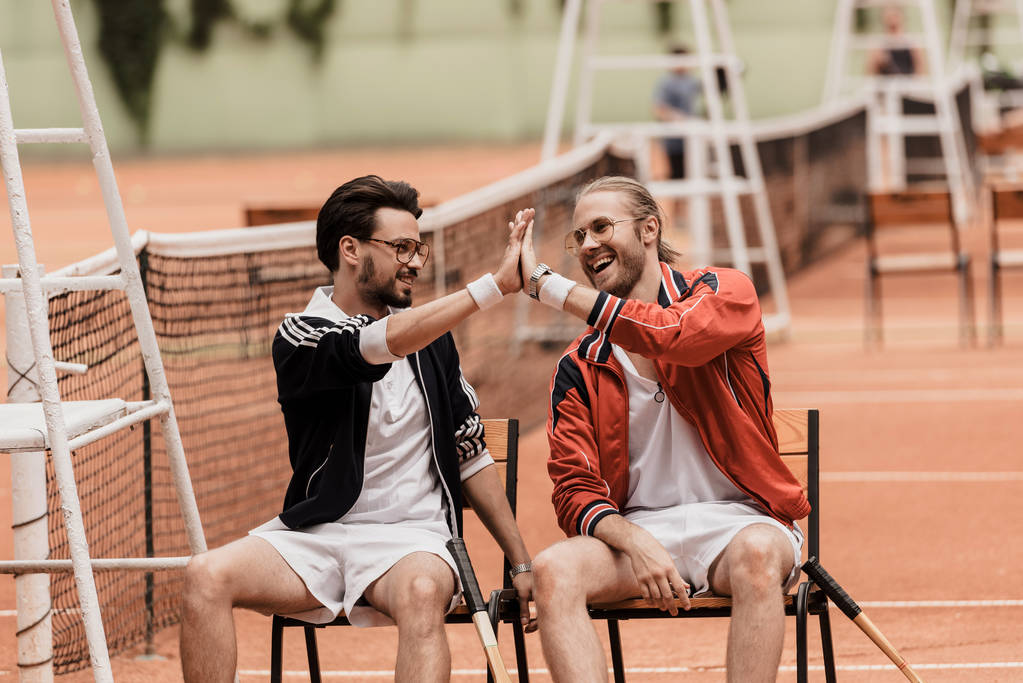 lächelnde Retro-gestylte Tennisspieler geben High Five auf dem Tennisplatz - Foto, Bild
