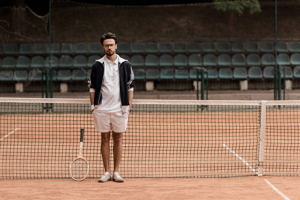 schöner Tennisspieler im Retro-Stil, der am Tennisplatz steht und in die Kamera schaut - Foto, Bild