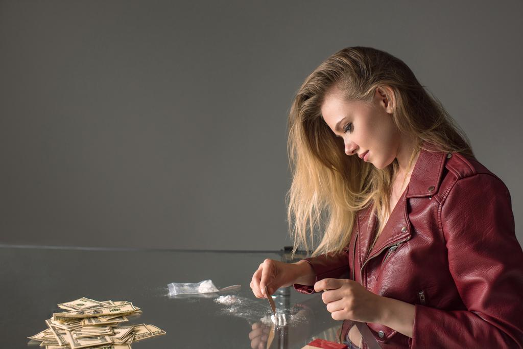 vista lateral de la joven adicta con cocaína en la mesa de cristal
 - Foto, Imagen
