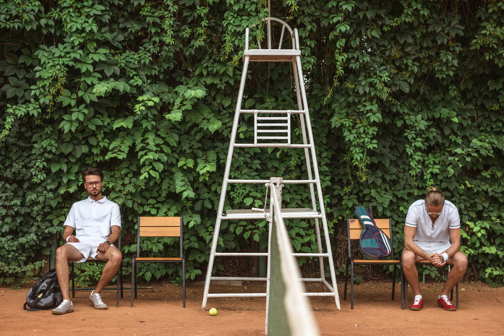 παίκτες του τένις που αναπαύεται μετά από εκπαίδευση στις καρέκλες στο γήπεδο - Φωτογραφία, εικόνα