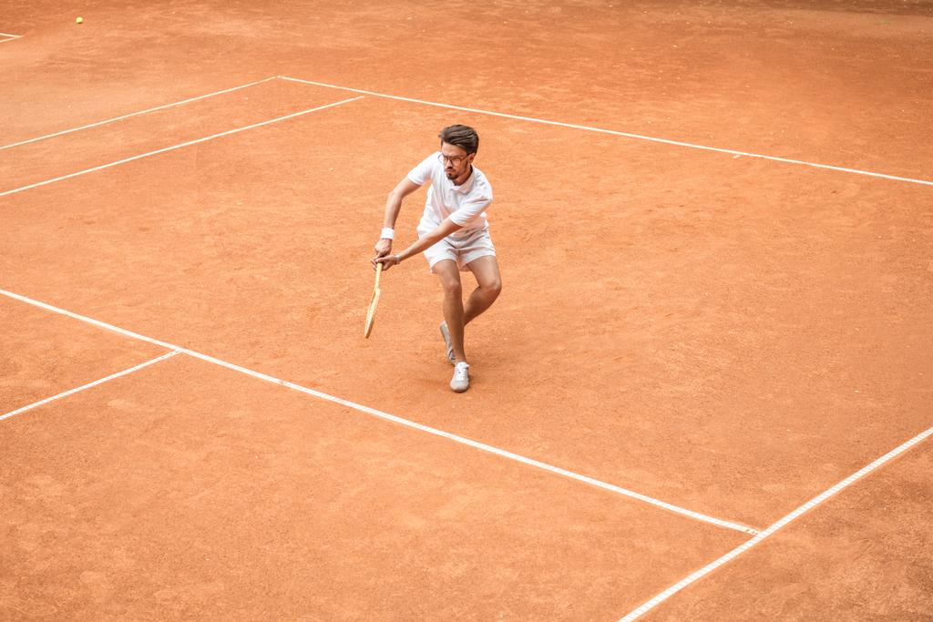 retro styled male tennis player with racket playing game on tennis court - Photo, Image