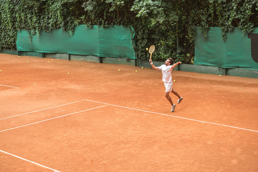 теннисист в стиле ретро прыгает с ракеткой на теннисном корте
 - Фото, изображение