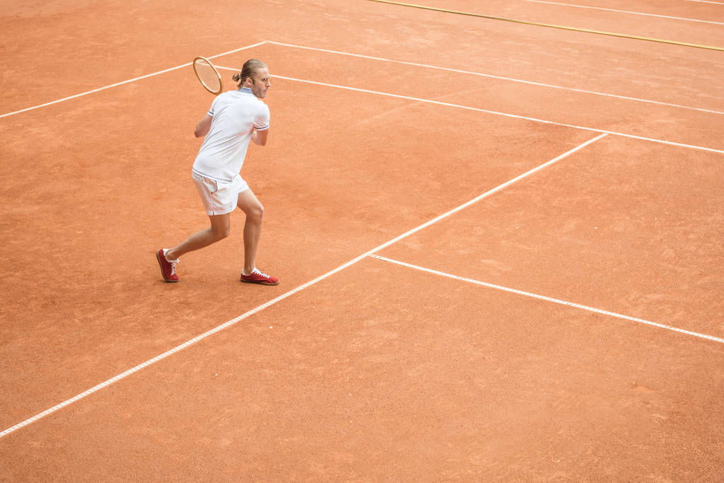 ouderwetse tennisser met racket op bruin Tennisbaan - Foto, afbeelding
