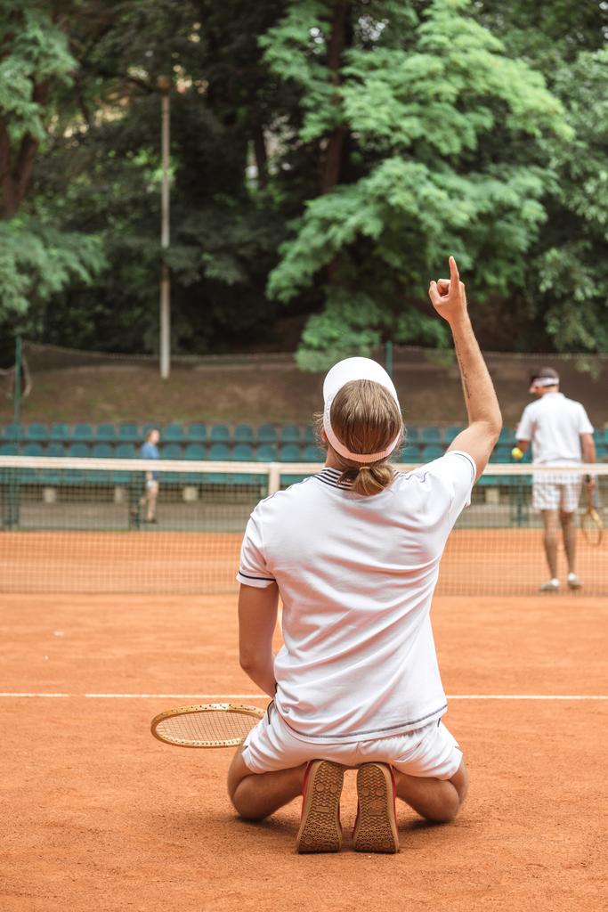 yukarı işaret ve sonra kazanan maç sahasında diz çökmüş eski tenis oyuncusu - Fotoğraf, Görsel