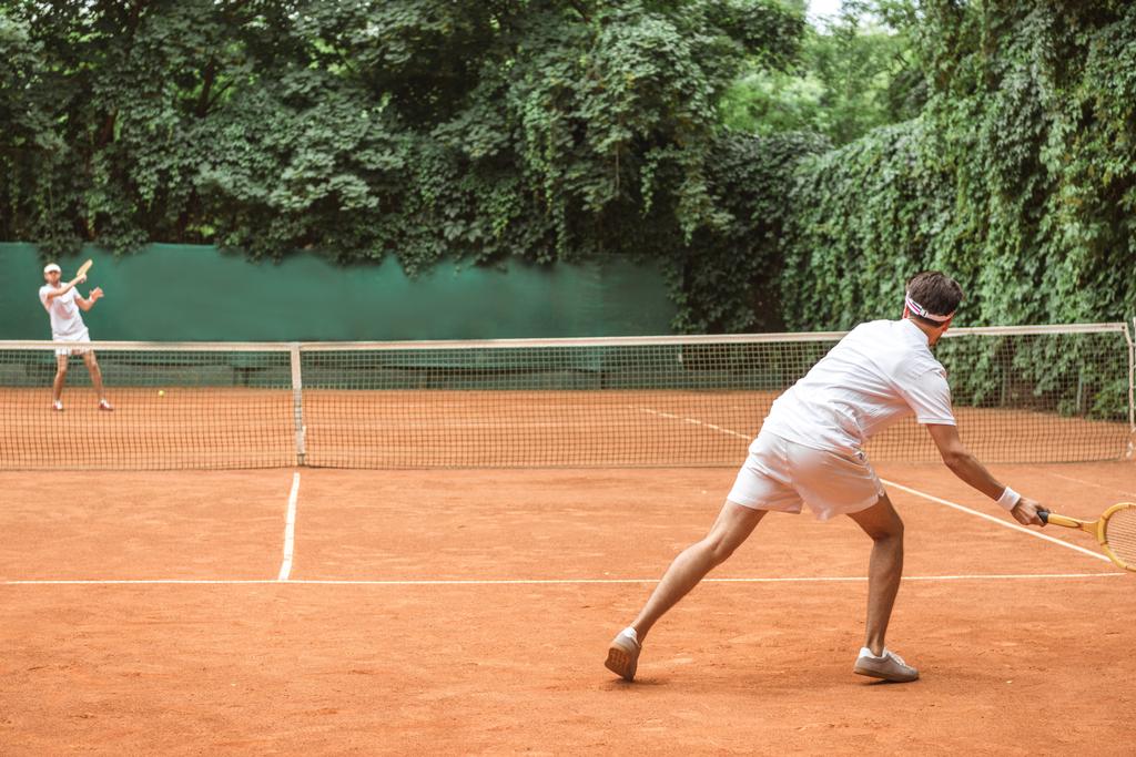 ντεμοντέ αθλητές παίζουν τένις με ξύλινες ρακέτες σε δικαστήριο - Φωτογραφία, εικόνα