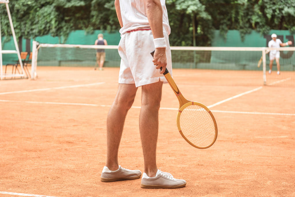 przycięte widzenia tenisista przytrzymanie retro drewniana rakieta i stojąc na kort tenisowy  - Zdjęcie, obraz