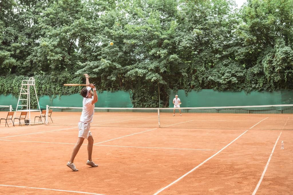 urheilijat pelaa tennistä puinen mailat kentällä
 - Valokuva, kuva