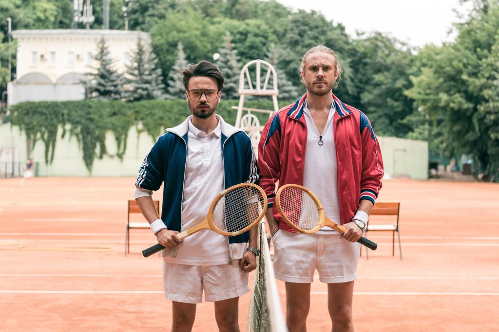 altmodische Freunde mit Holzschlägern posieren auf Tennisplatz mit Netz - Foto, Bild