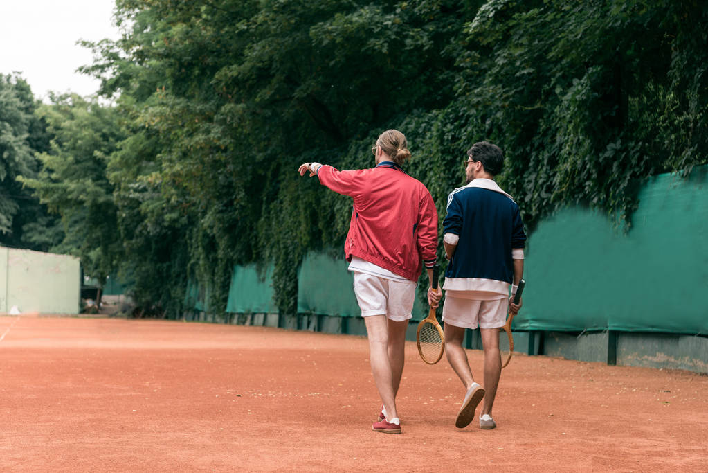 вид сзади друзей в стиле ретро с деревянными рейнджерами, прогуливающимися по теннисному корту
 - Фото, изображение