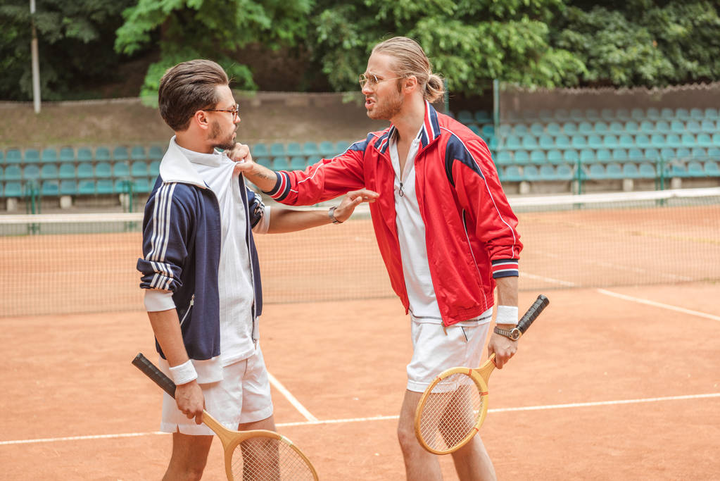 Wütende Sportler mit Holzschlägern auf Tennisplatz aneinandergeraten - Foto, Bild