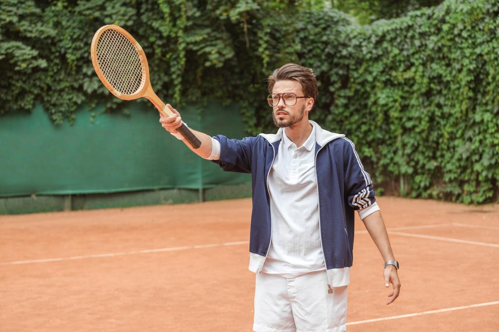 Tenis kortunda ahşap raket ile işaret eden yakışıklı tenis oyuncusu - Fotoğraf, Görsel