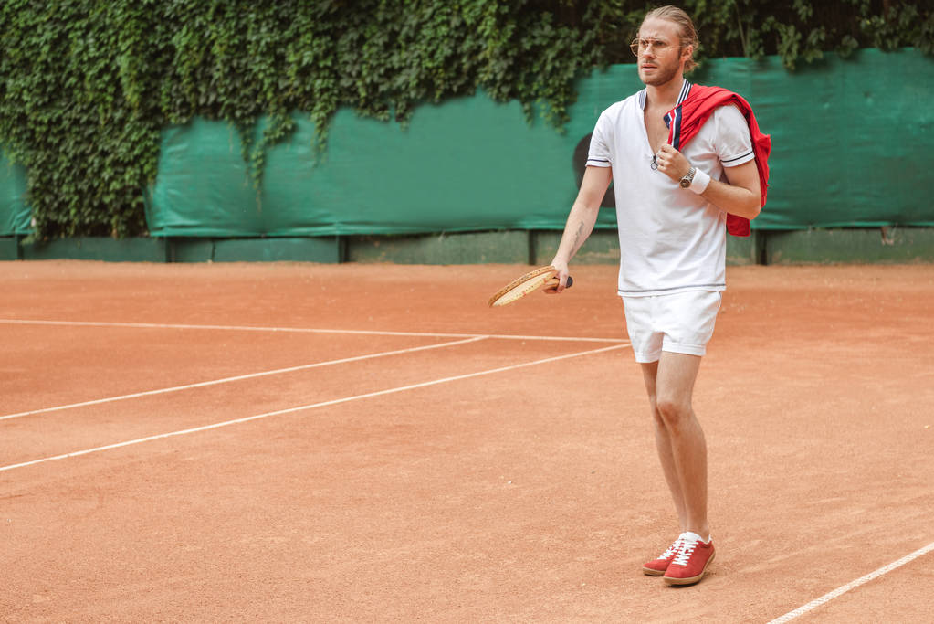 handsome man in sportswear with retro wooden racket on tennis court - Photo, Image