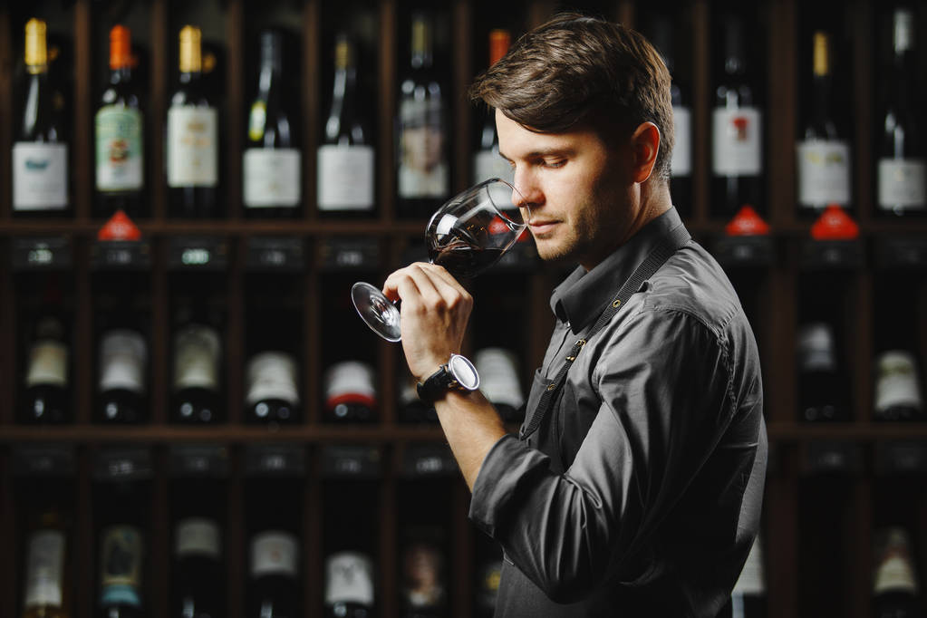 Бокал красного вина на заднем плане, мужчина сомелье признательный напиток - Фото, изображение