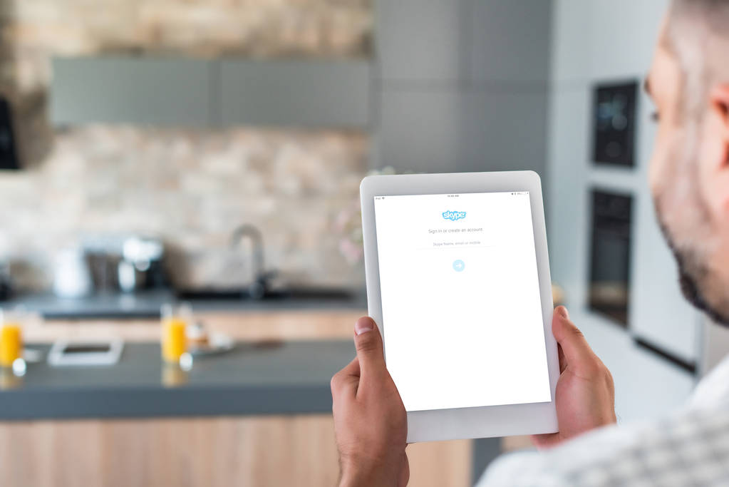 valikoiva painopiste mies käyttää digitaalista tabletti skype logo ruudulla keittiössä
  - Valokuva, kuva