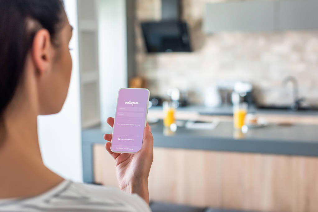 селективный фокус женщины, держащей смартфон с логотипом Instagram на экране на кухне
 - Фото, изображение