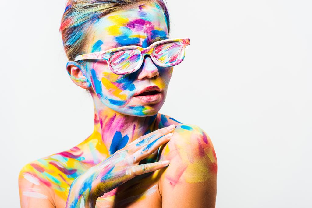 menina atraente com arte corporal brilhante colorido e óculos de sol tocando ombro isolado no branco
 - Foto, Imagem