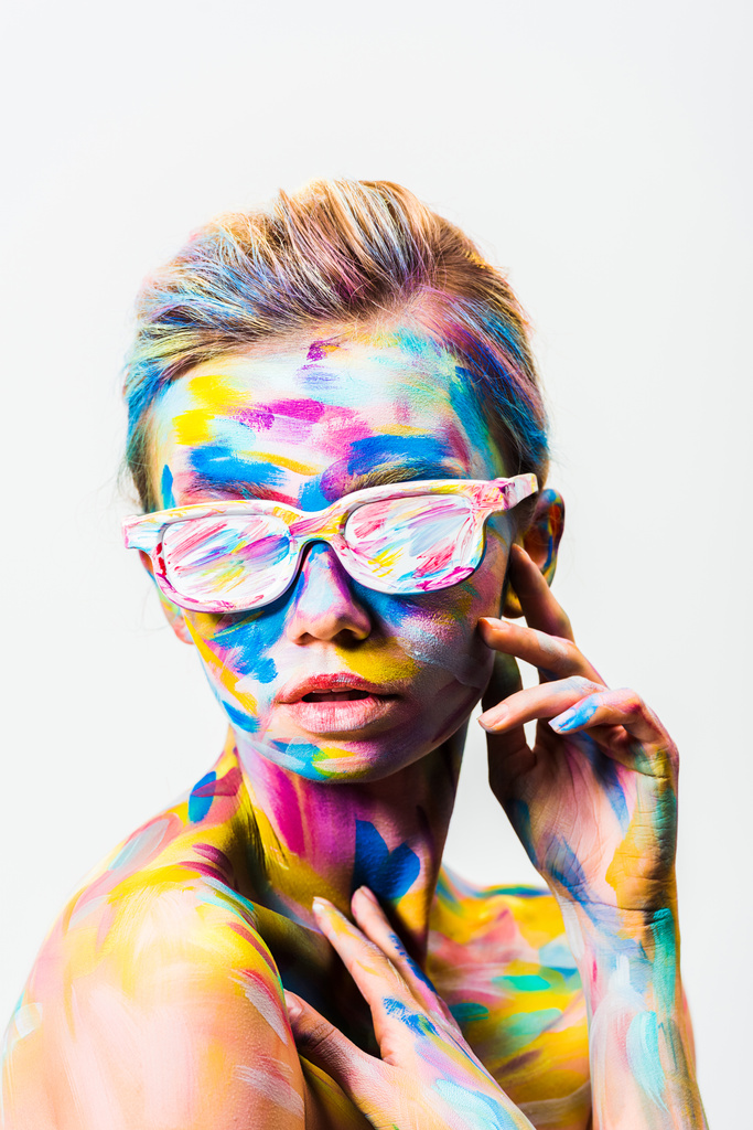 atraktivní dívka s barevnými světlé bodyart a sluneční brýle, dotýká sama sebe izolované na bílém - Fotografie, Obrázek