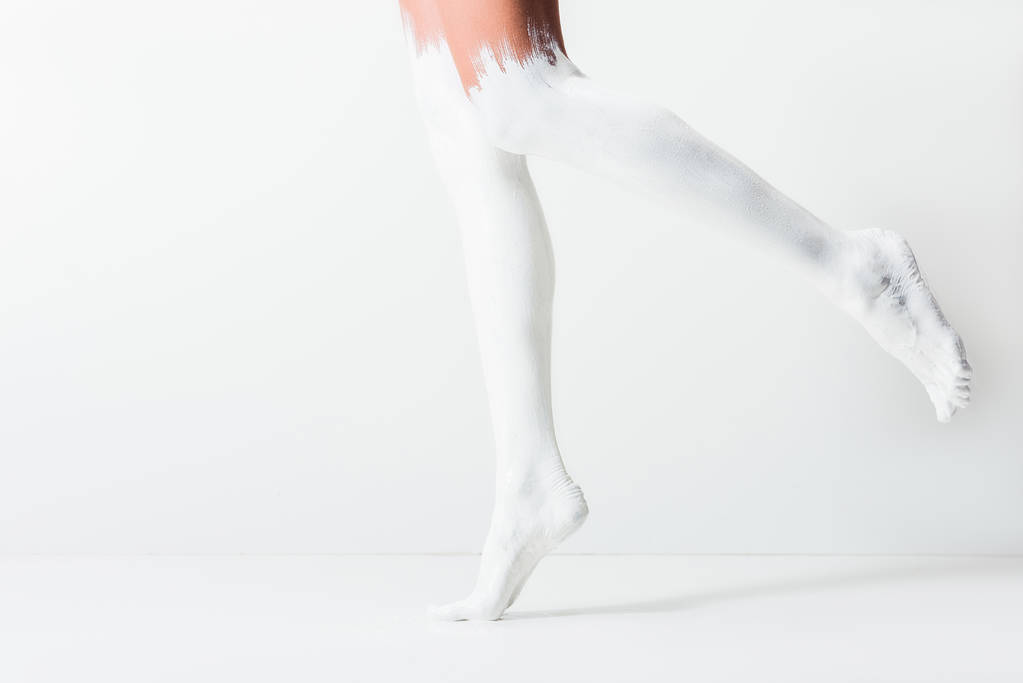 beyaz zemin üzerinde atlama beyaz boya ile boyalı bacaklar ile kız resim kırpılmış - Fotoğraf, Görsel