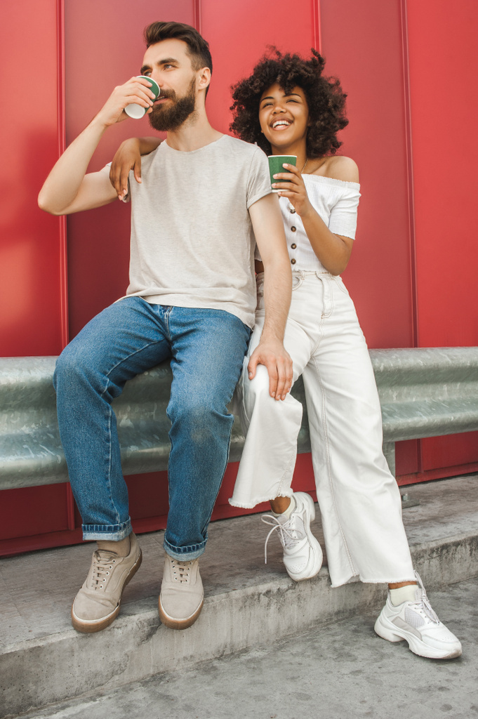полный обзор стильной молодой межрасовой пары, пьющей кофе из бумажных стаканчиков на улице
 - Фото, изображение