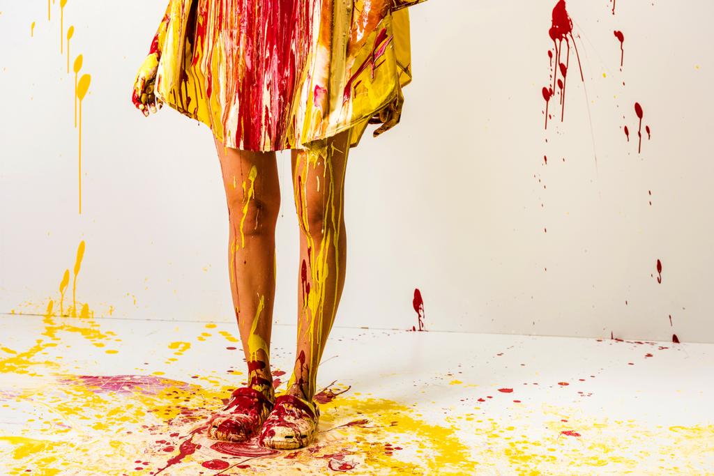 обрізане зображення жінки, пофарбованої жовтими та червоними фарбами, що стоять на підлозі
  - Фото, зображення