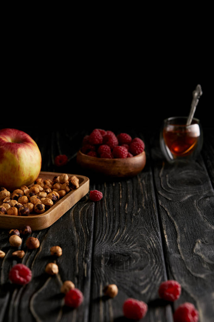 hazelnuts with apple and raspberries on black wooden table  - Photo, Image
