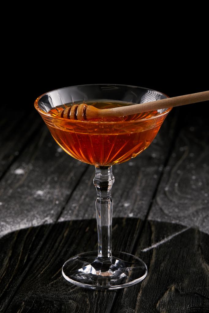 Close-up shot sklenice medu s dřevěnou lžící na černý dřevěný stůl - Fotografie, Obrázek