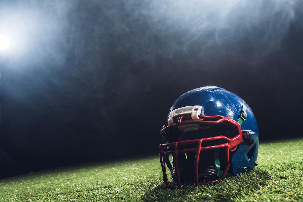 close-up shot of american football helmet on green grass with white smoke above - Photo, Image