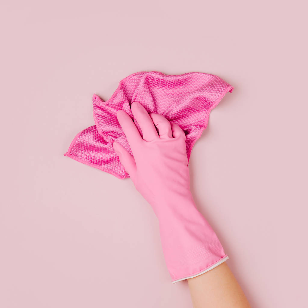 Nainen käsi puhdistus vaalean vaaleanpunainen tausta. Siivous- tai siivouskonseptin tausta. Kopioi tilaa. Tasainen, ylhäältä näkymä
. - Valokuva, kuva
