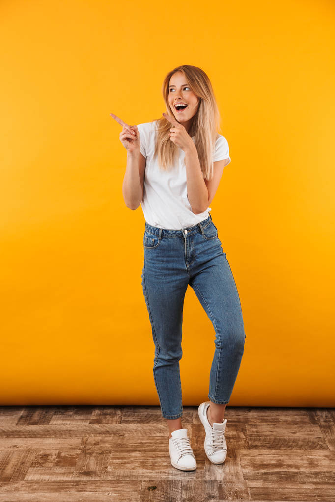 Портрет щасливої молодої блондинки, що вказує на простір копіювання ізольовано на жовтому тлі
 - Фото, зображення