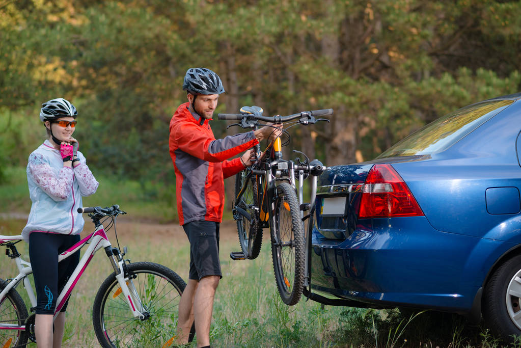 junges Paar demontiert Mountainbikes vom Fahrradständer am Auto. Erlebnis- und Familienreisekonzept. - Foto, Bild