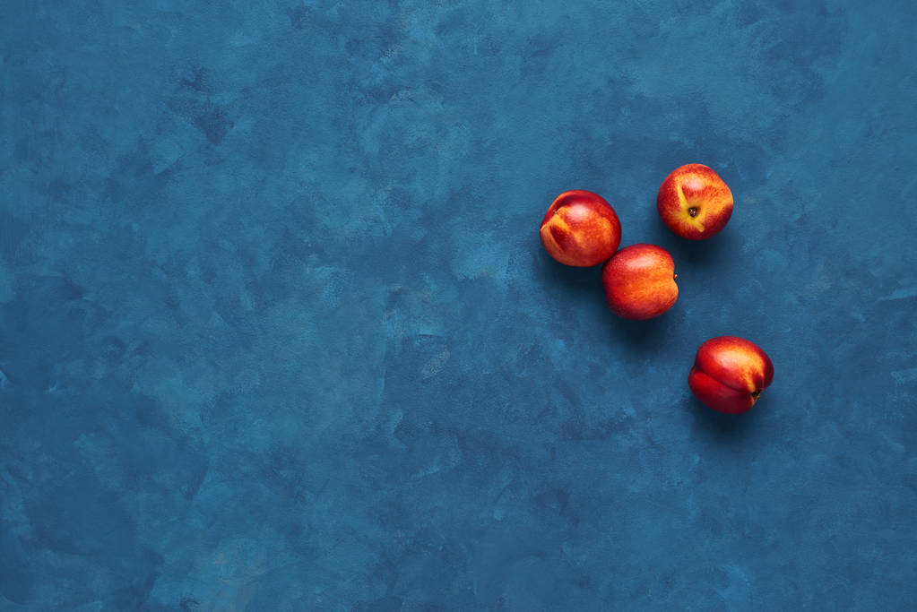 Pose plate de nectarines fraîches fruits sur fond bleu. Vue supérieure avec espace de copie
. - Photo, image