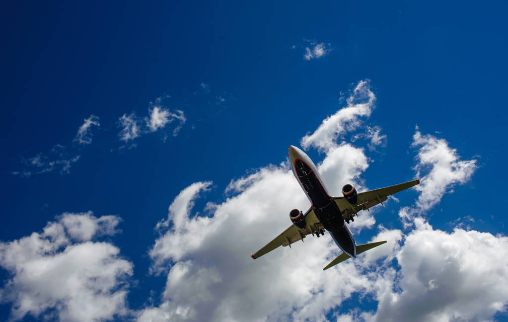 Het vliegtuig op een achtergrond van blauwe hemel en witte wolken. - Foto, afbeelding