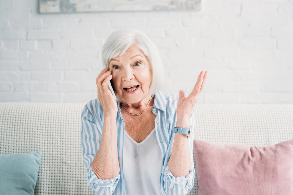 портрет емоційної старшої жінки, що розмовляє на смартфоні вдома
 - Фото, зображення