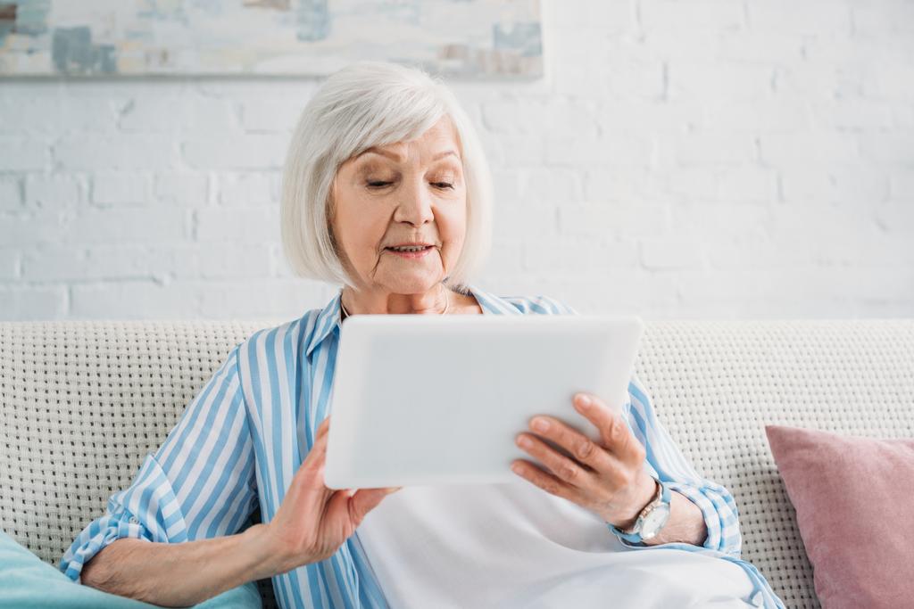 retrato de la mujer mayor usando la tableta en el sofá en casa
 - Foto, Imagen