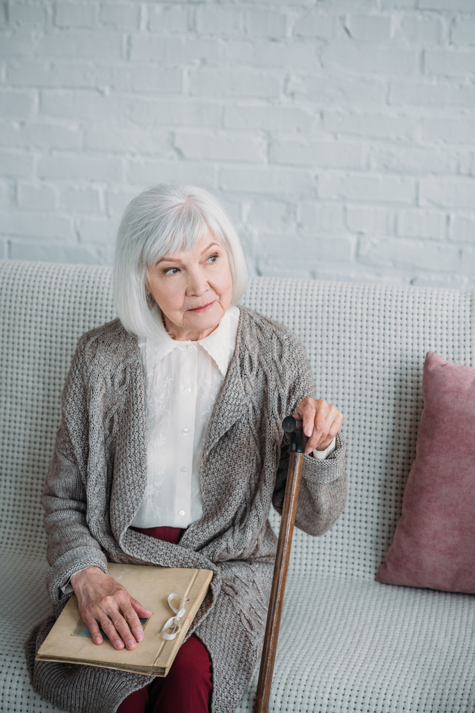 dame âgée réfléchie avec album photo reposant sur le canapé à la maison
 - Photo, image